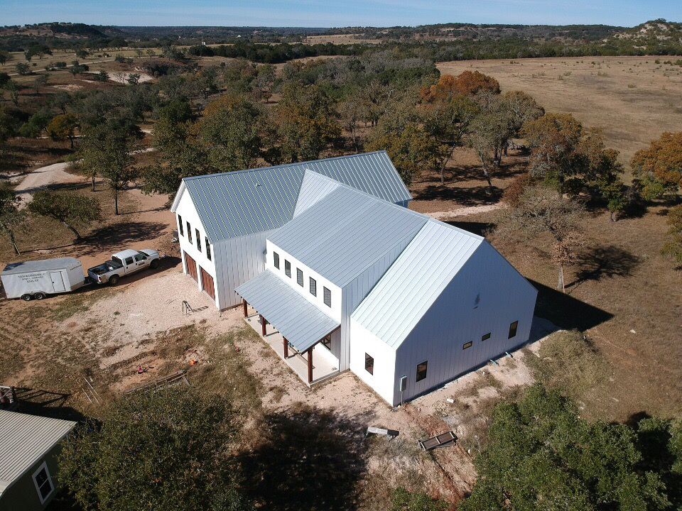 Aerial perspective of white modern farm buildings with metal roofs.