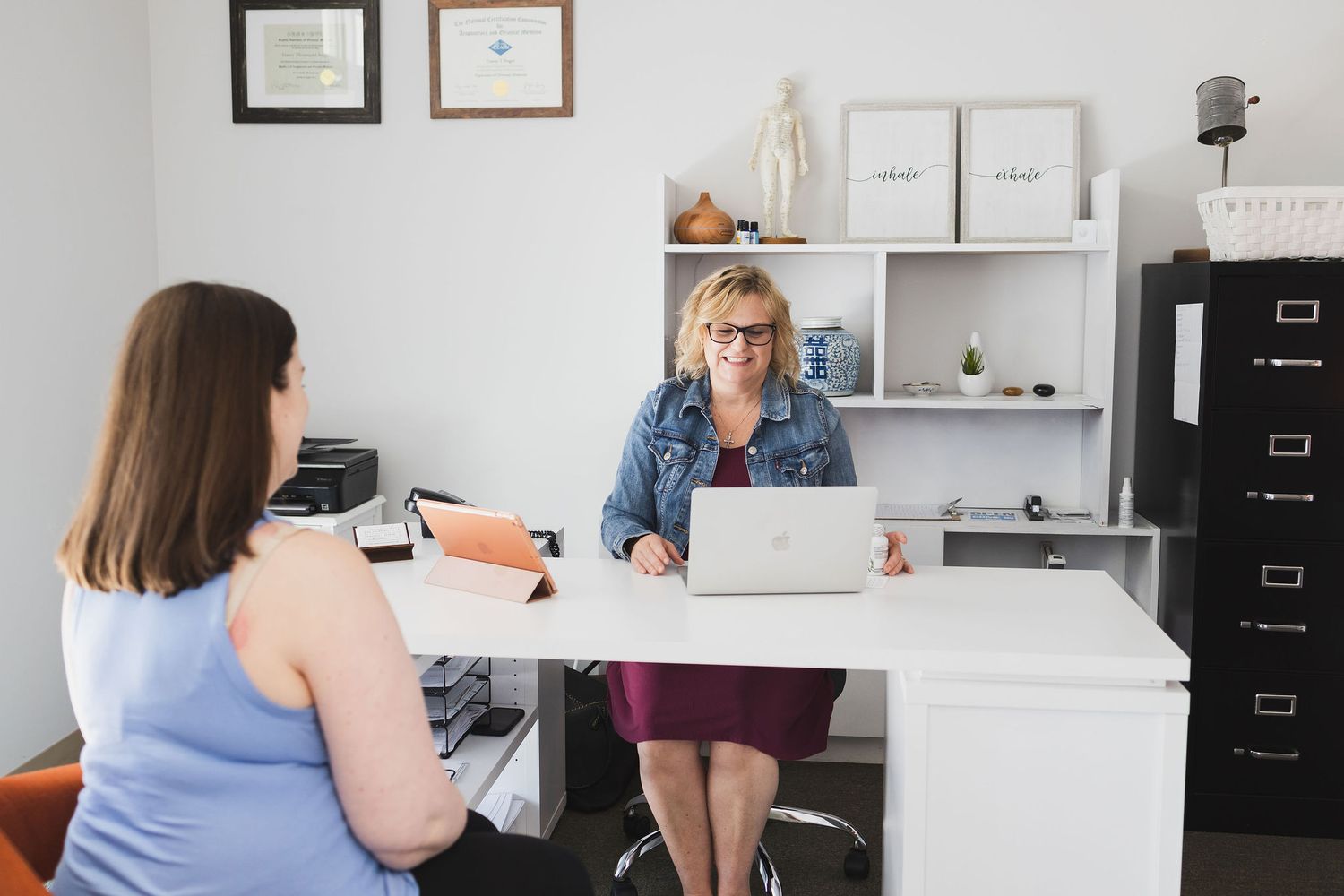 Maple Valley Acupuncture, WA branding photo of female receptionist sitting at laptop booking next appointment for client after her session
