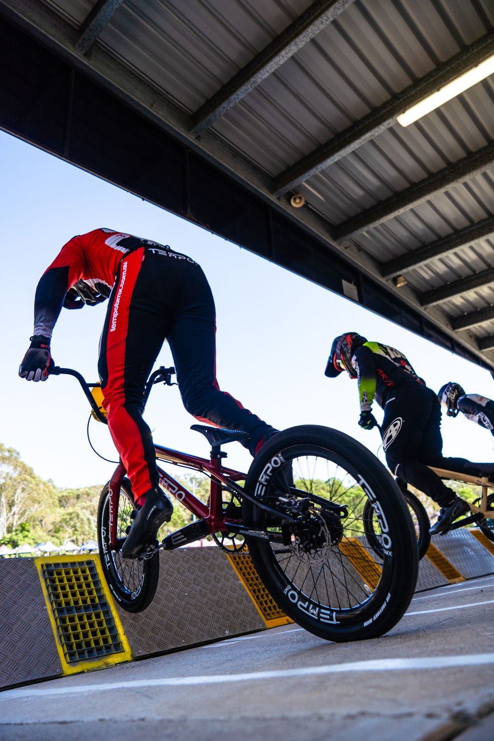 A sequence of BMX bike trick progression shots showing a rider performing a flip maneuver off a ramp.