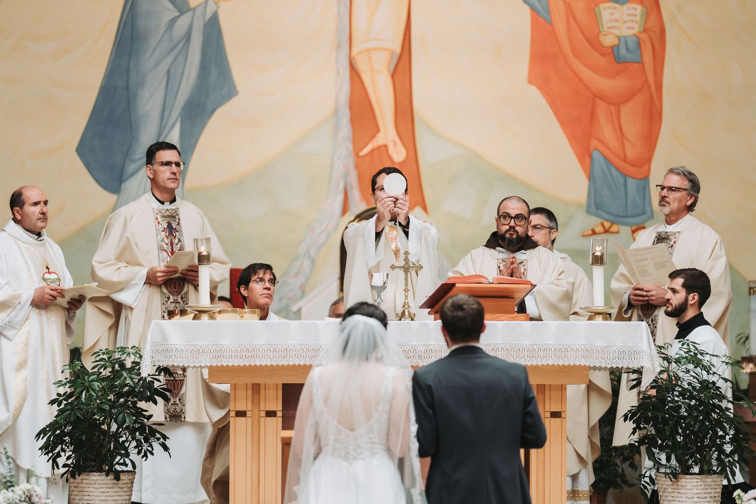 Catholic wedding ceremony at altar with priests and clergy celebrating mass during traditional church service.
