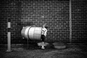 Black and white image of a vintage milk container against a brick wall.
