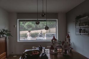 Cozy interior room with window view and decorative dollhouse on dining table.
