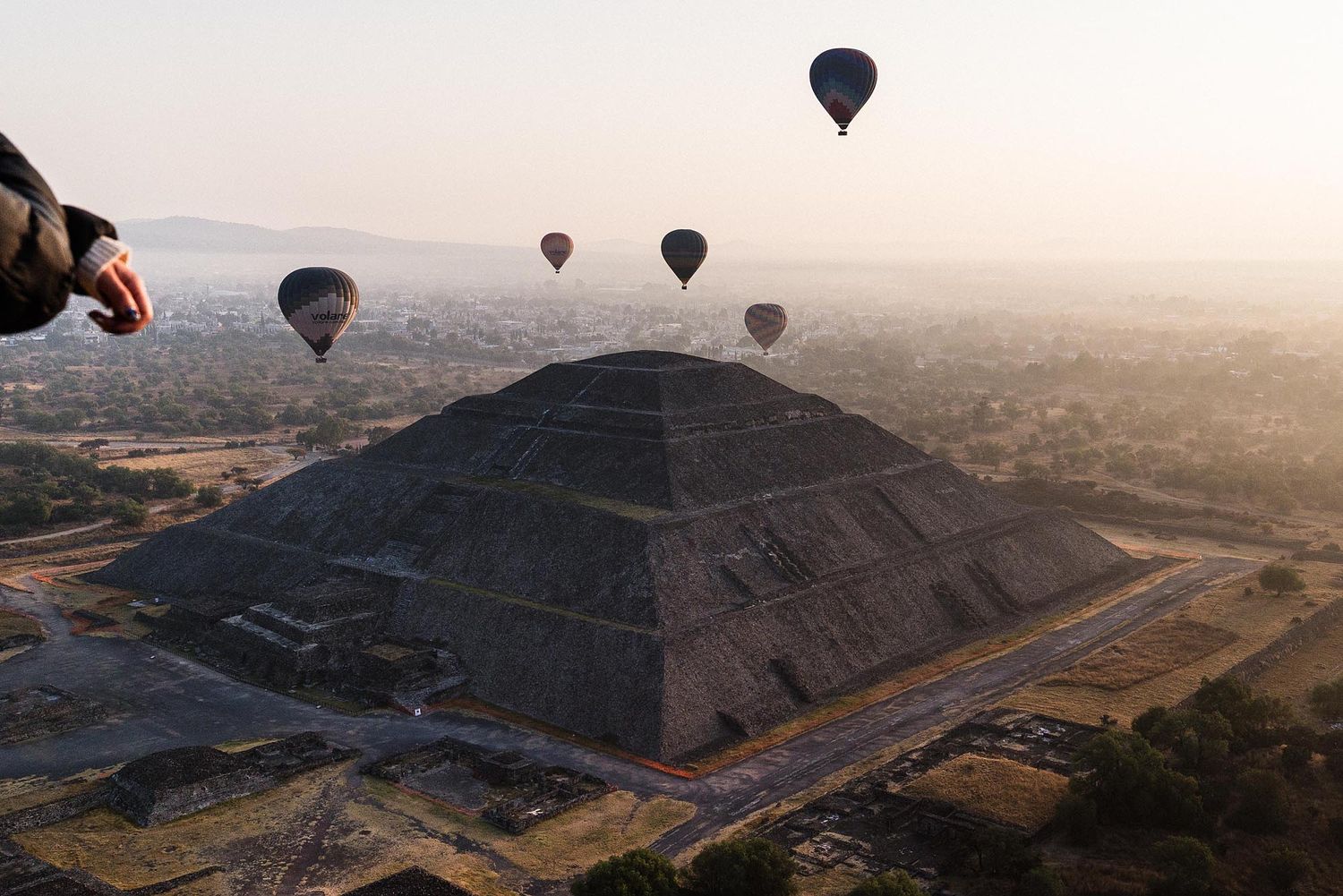 Hot air balloons floating over ancient pyramids in Egypt during a misty sunrise, creating a magical aerial landscape.