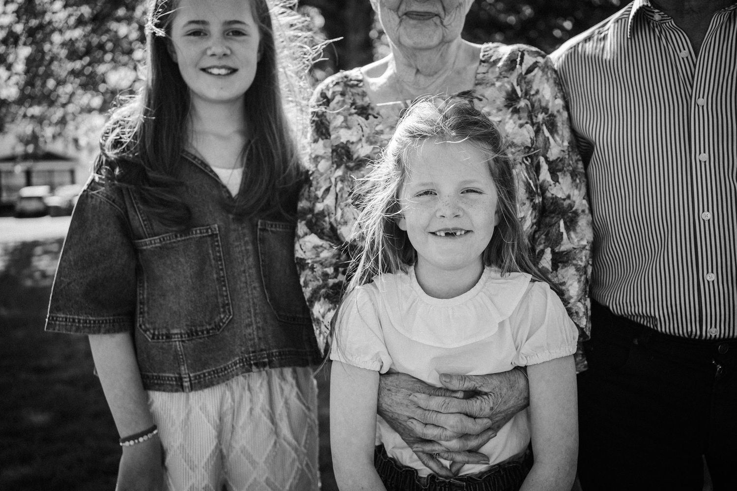 Black and white candid portrait photograph showing people smiling outdoors in a natural setting.