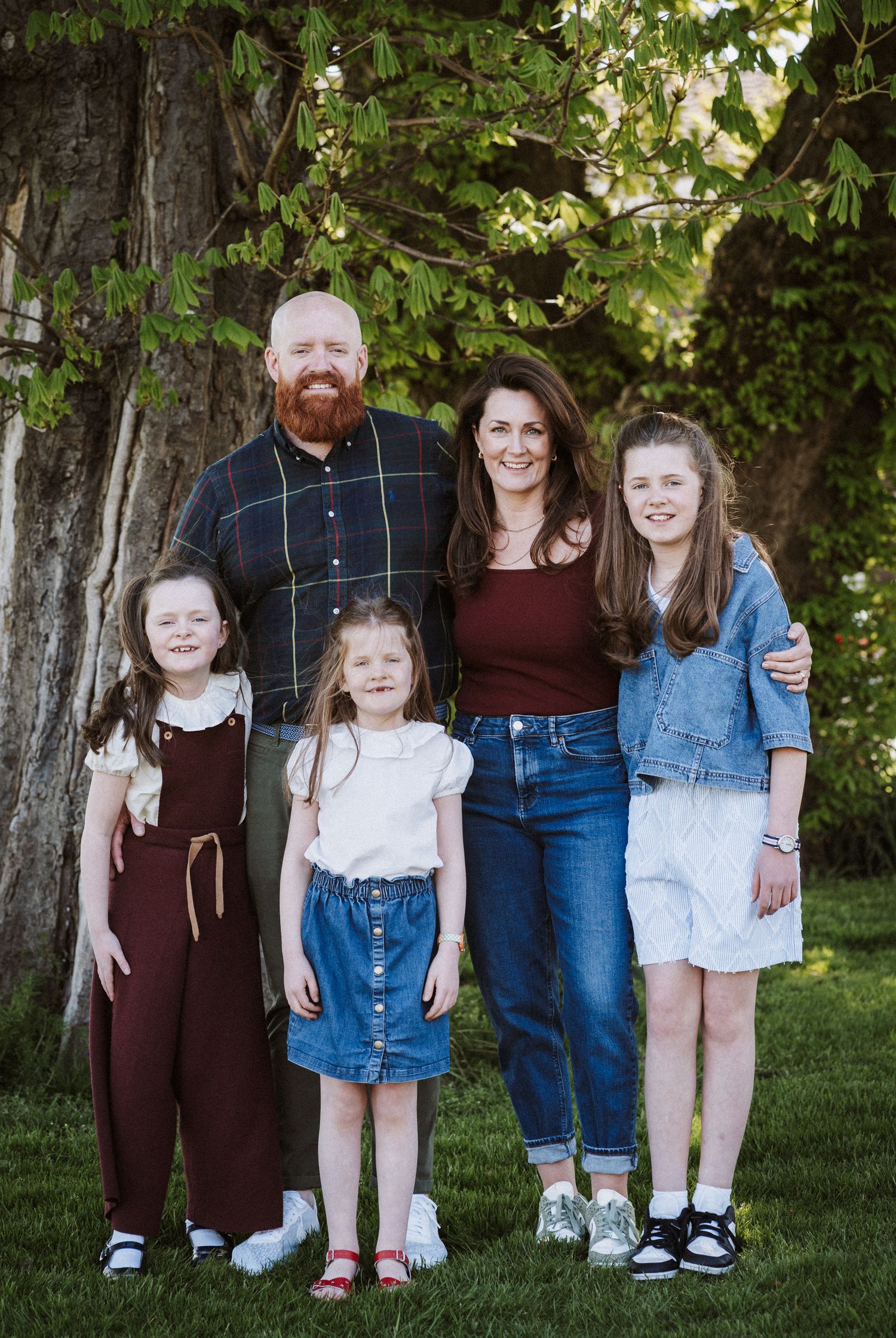 Multiple candid shots of a family group posing together outdoors against a backdrop of green trees.