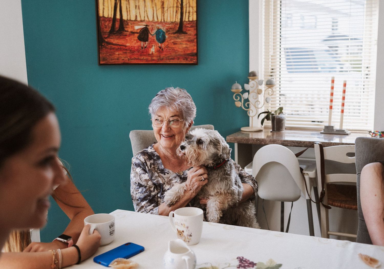A series of candid moments showing people enjoying tea and conversation at a dining table with a teal wall backdrop.