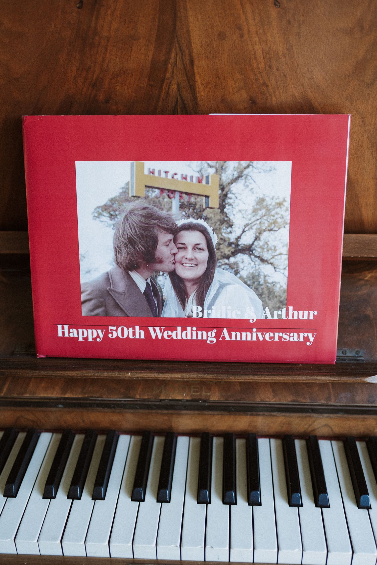 Piano keyboard with red 50th wedding anniversary photo cards displayed along the music rack above the keys.