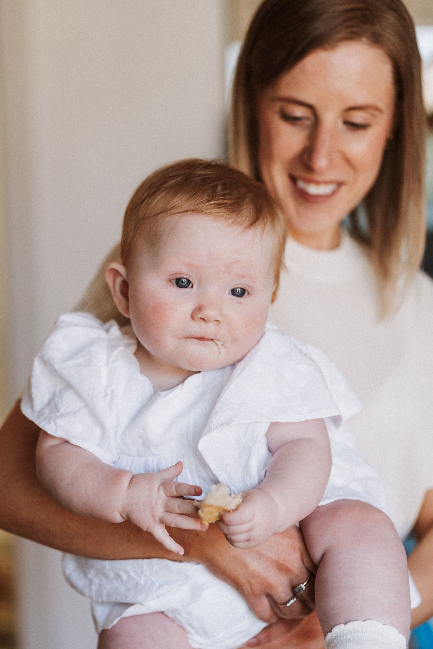 A baby in a white dress smiles while being held, shown in a series of connected photos against a light background.