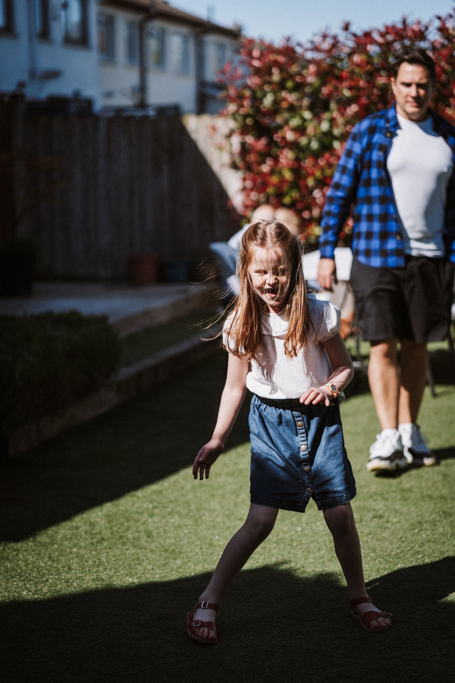 A playful scene of outdoor fun and movement on a sunny day with green grass and garden surroundings.