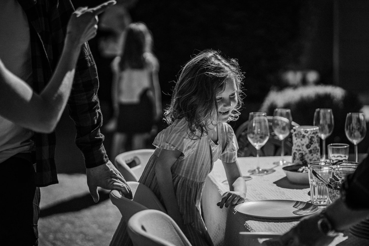 Black and white candid shot at a dinner table with wine glasses and place settings during an evening event.