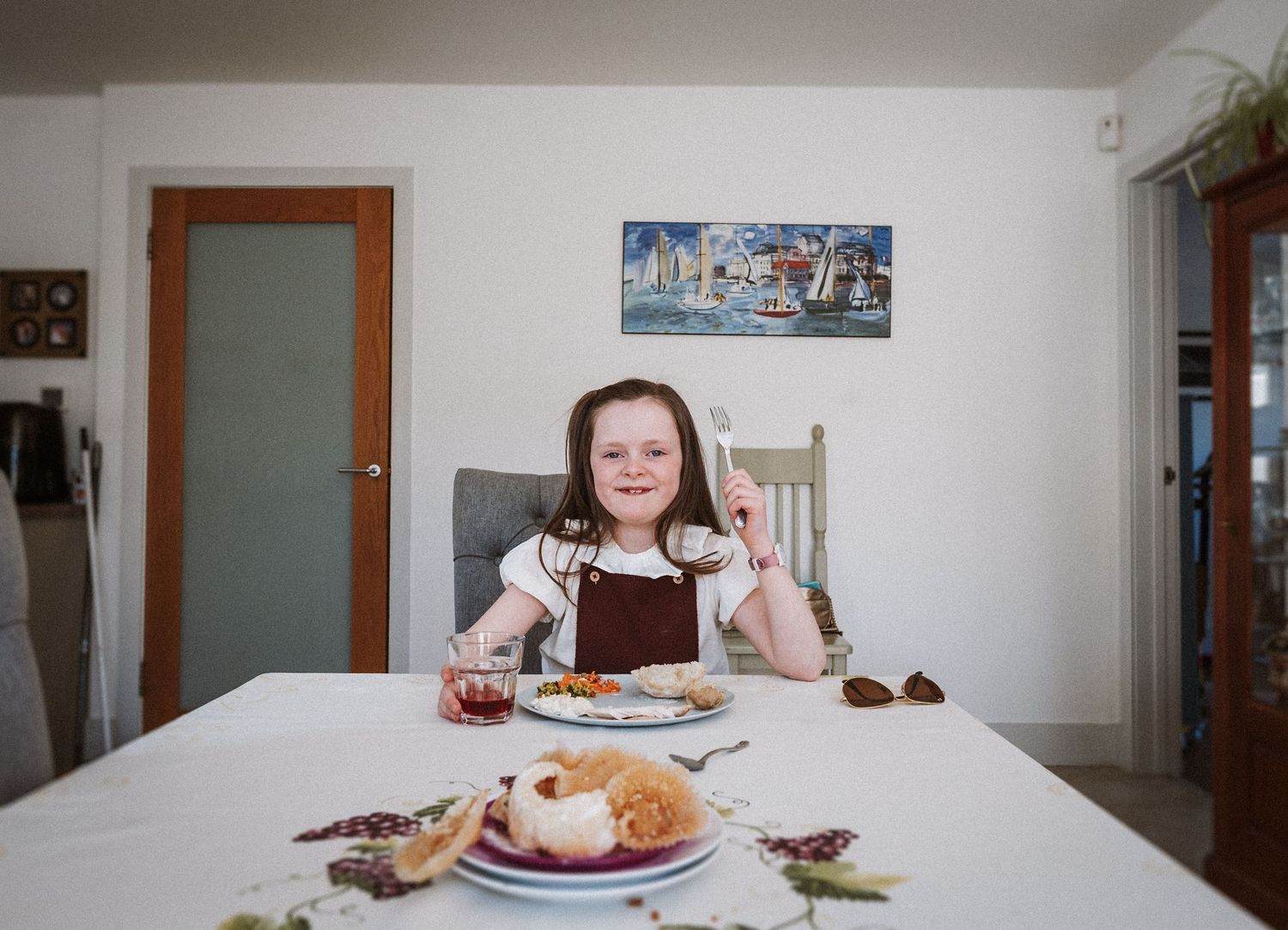 A long panoramic view of a dining room table with plates of food and people seated around it.