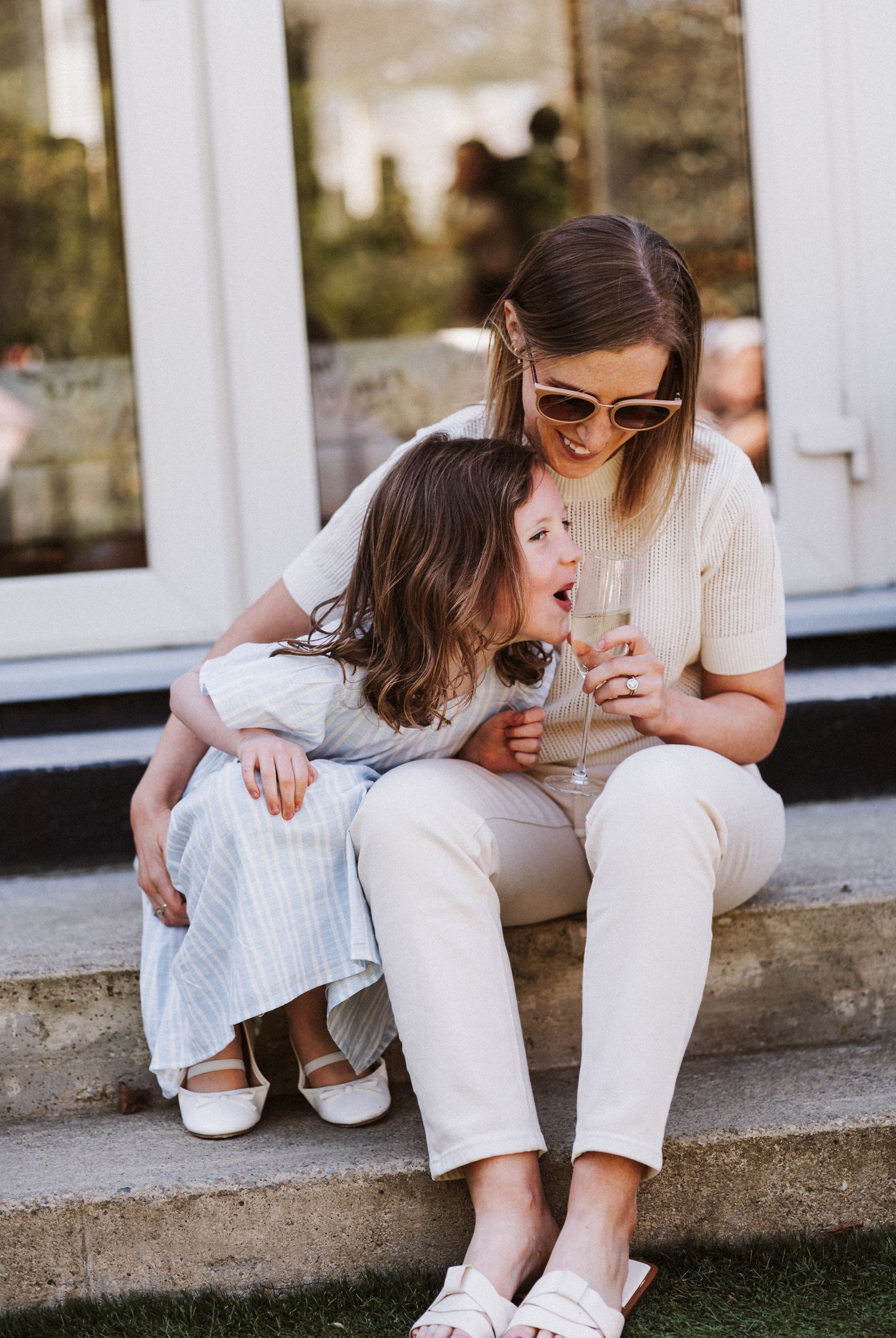 A tender moment shared on concrete steps as they enjoy drinks together on a sunny afternoon.