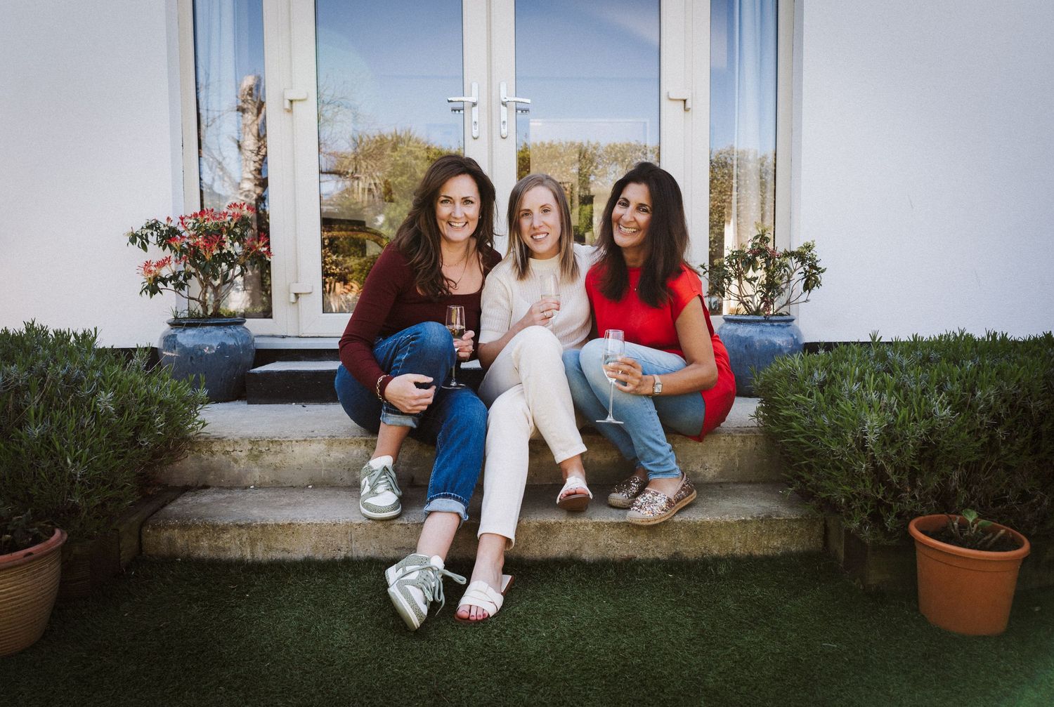 A group sits together on white steps outside a building, creating a casual and relaxed outdoor scene.
