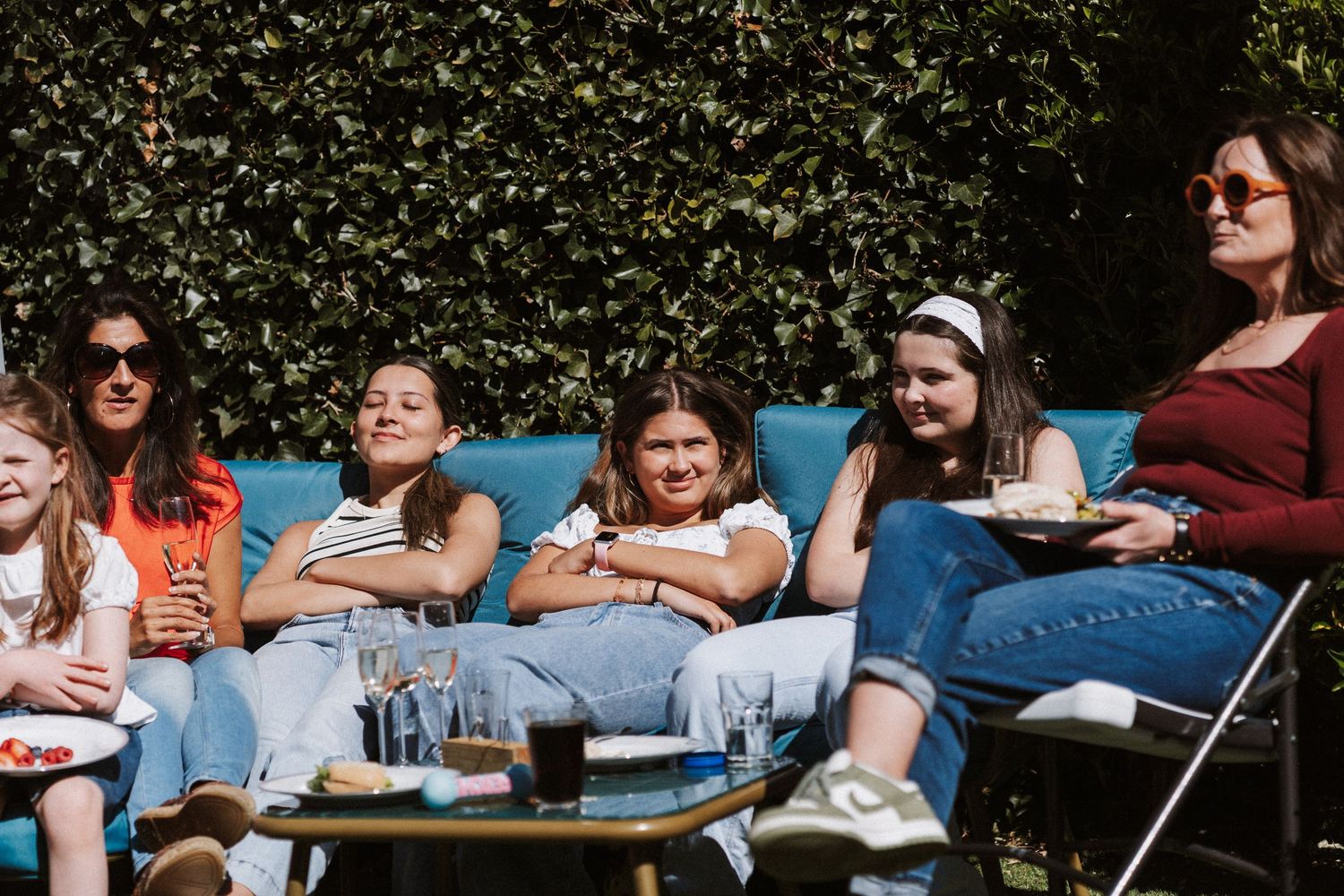 A group of people enjoying an outdoor gathering at a picnic table on a sunny day.