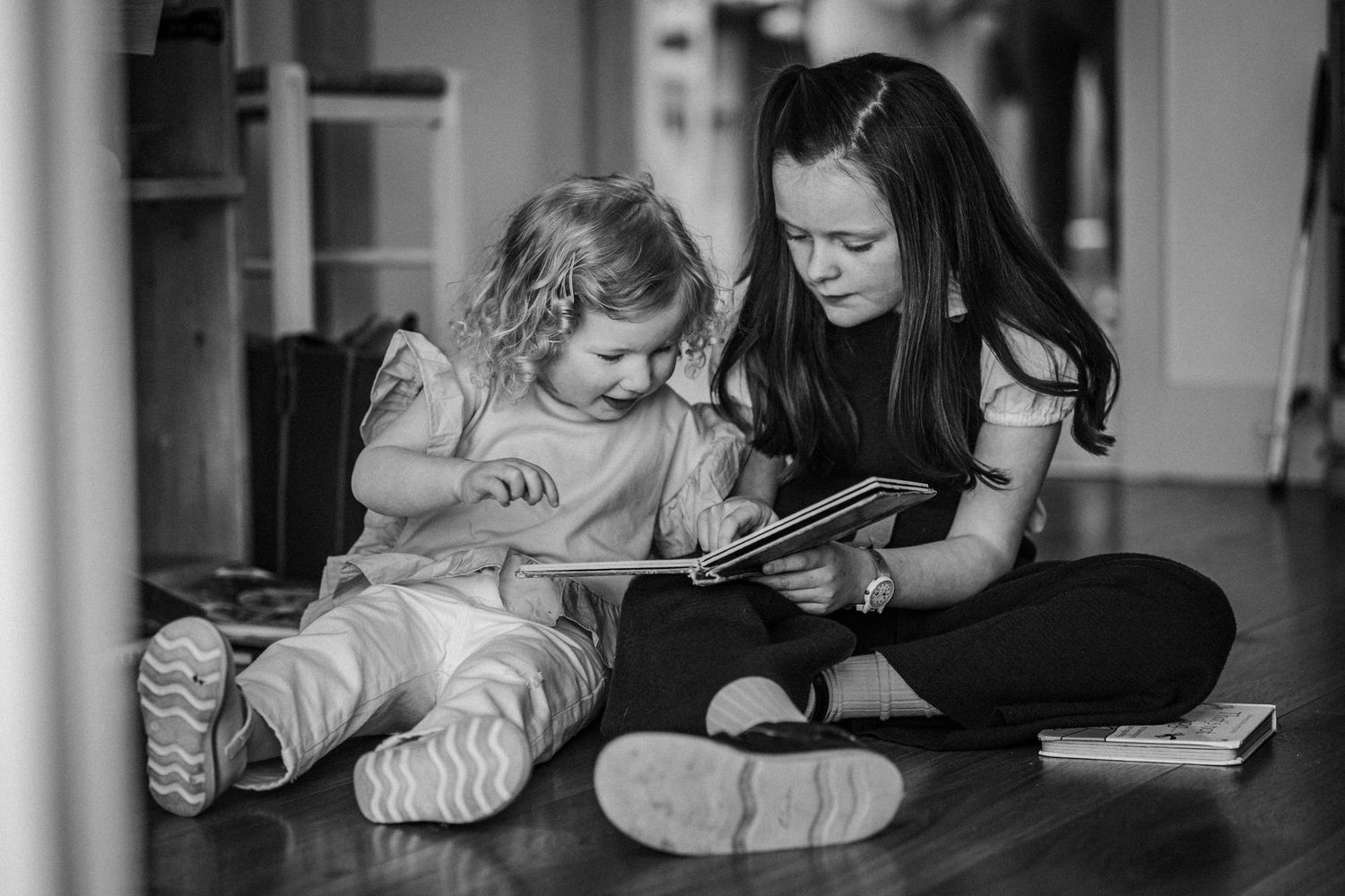 A series of black and white photos showing children reading books while lying on the floor.