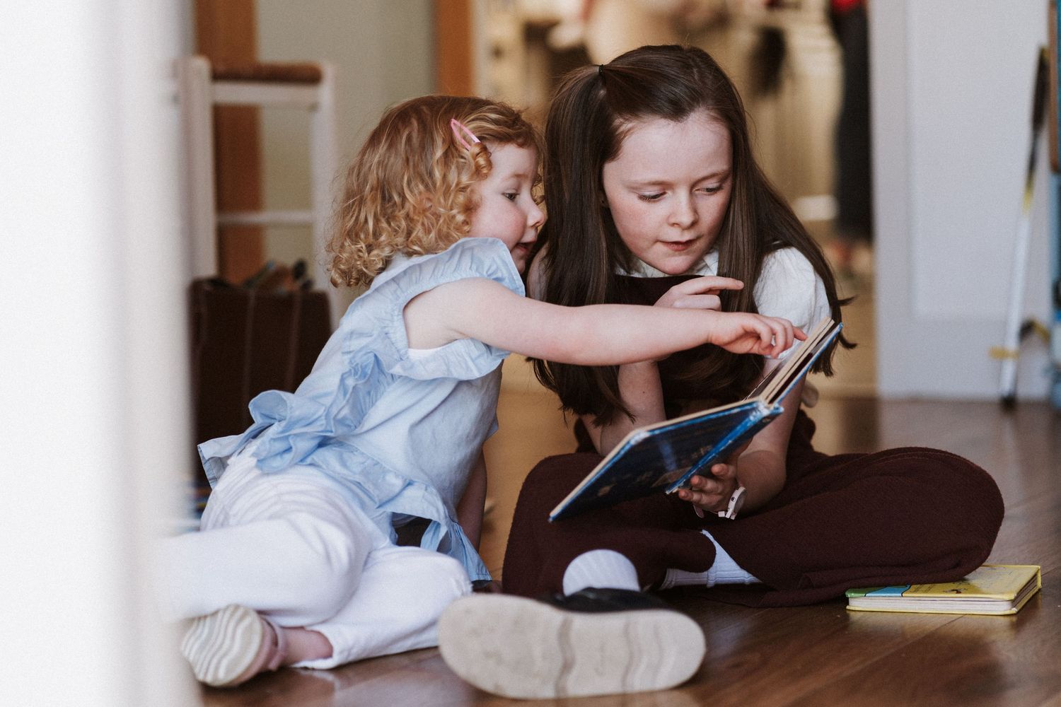 Two people sit closely together while looking at a mobile device in a bright indoor setting.
