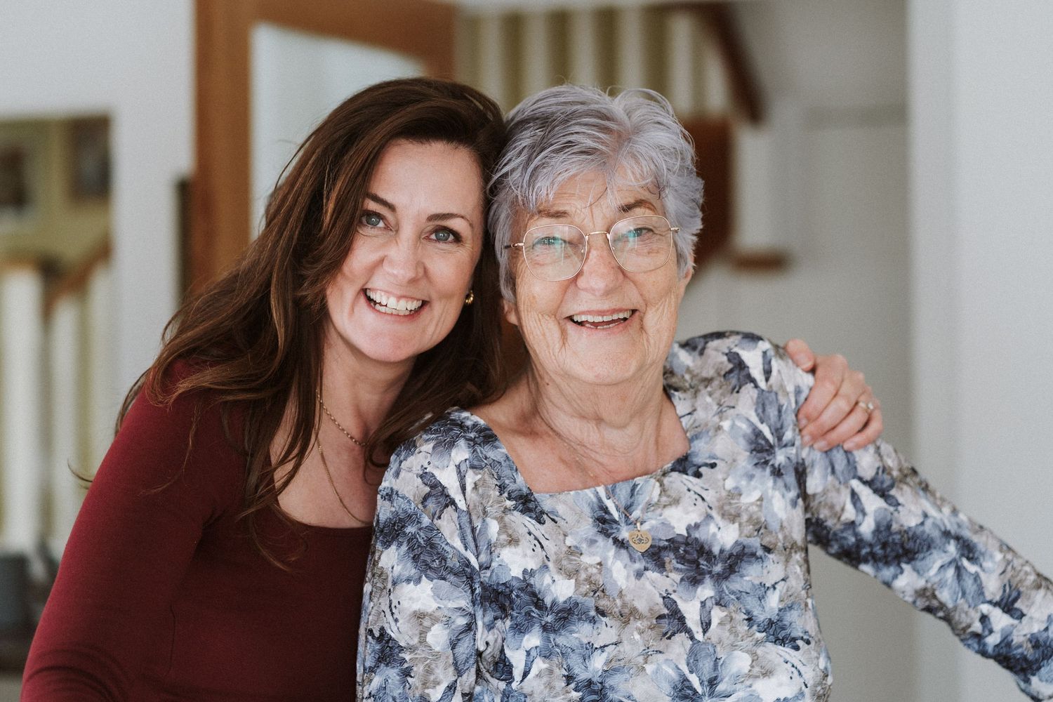 Two people embrace and smile while sitting together on a couch in a warmly lit living room.