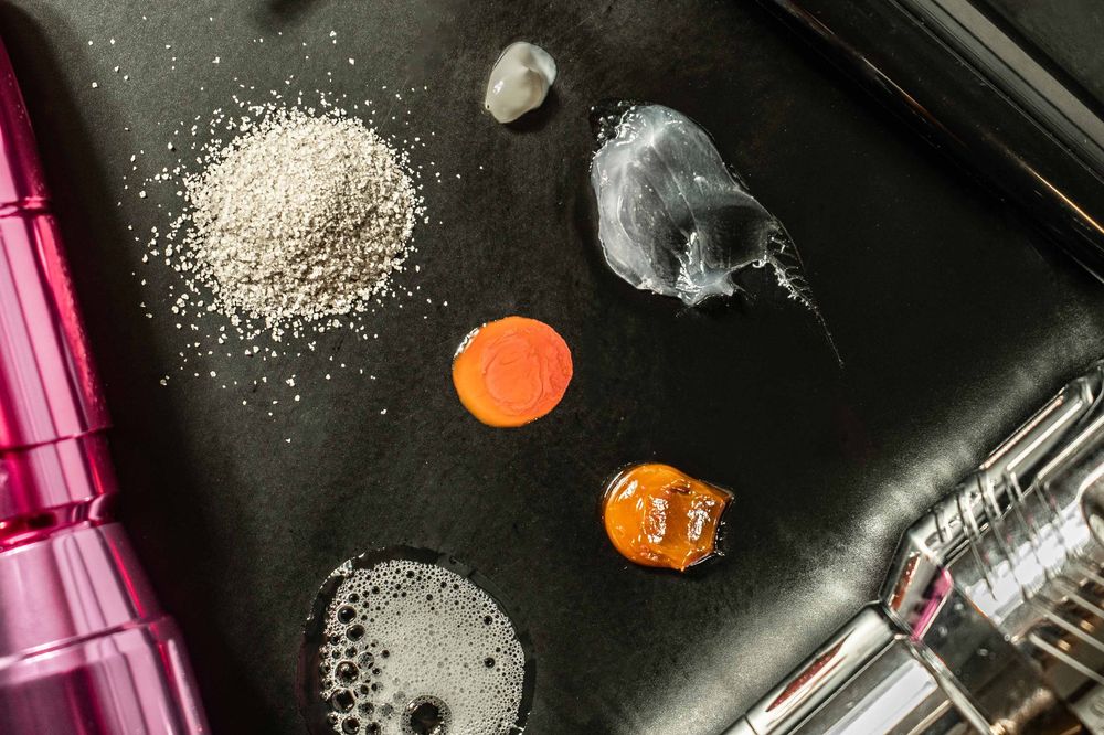 A messy kitchen counter with scattered flour, cooking utensils, and pink measuring cups in view.
