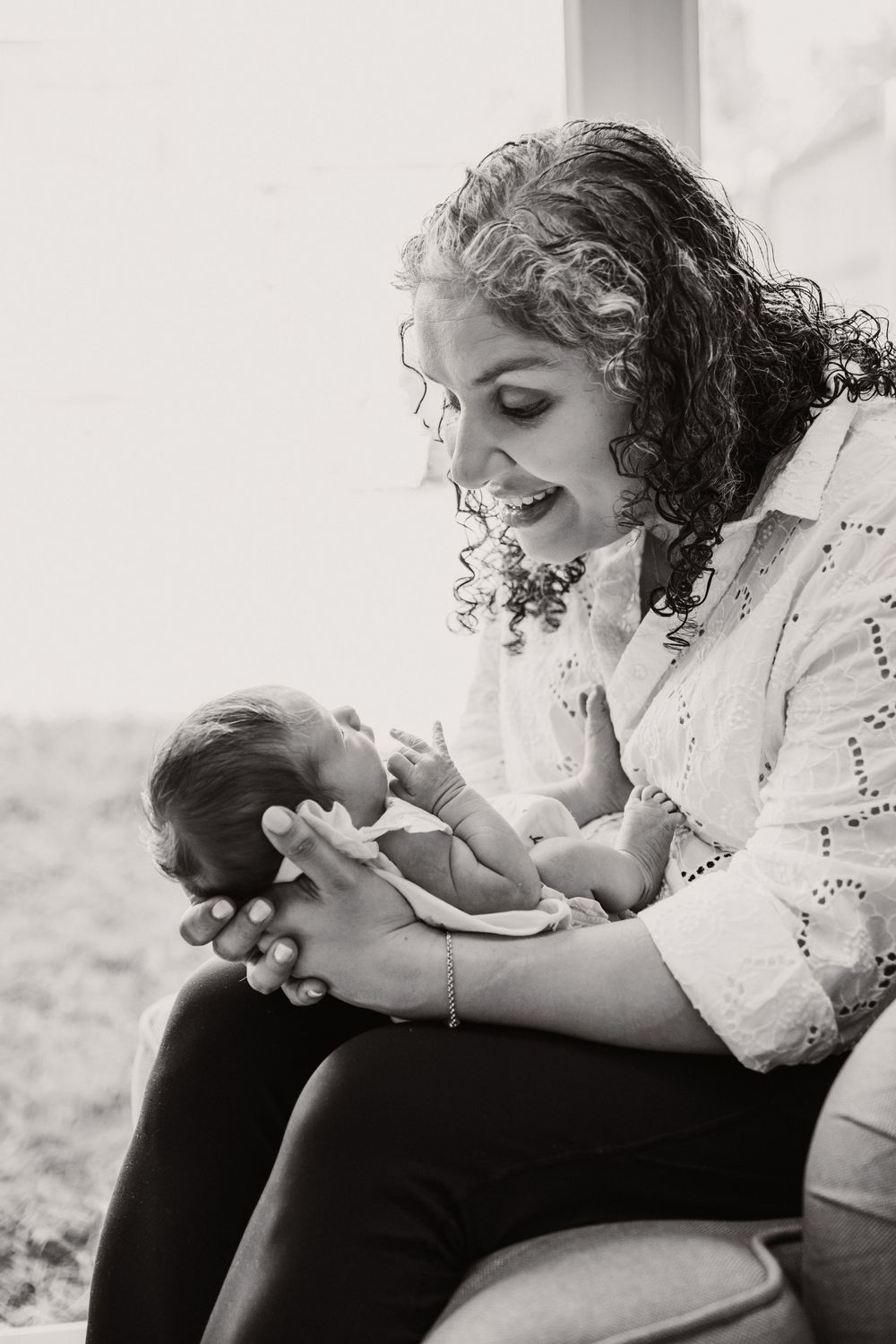 A tender black and white portrait of a mother sharing a joyful moment with her newborn baby.