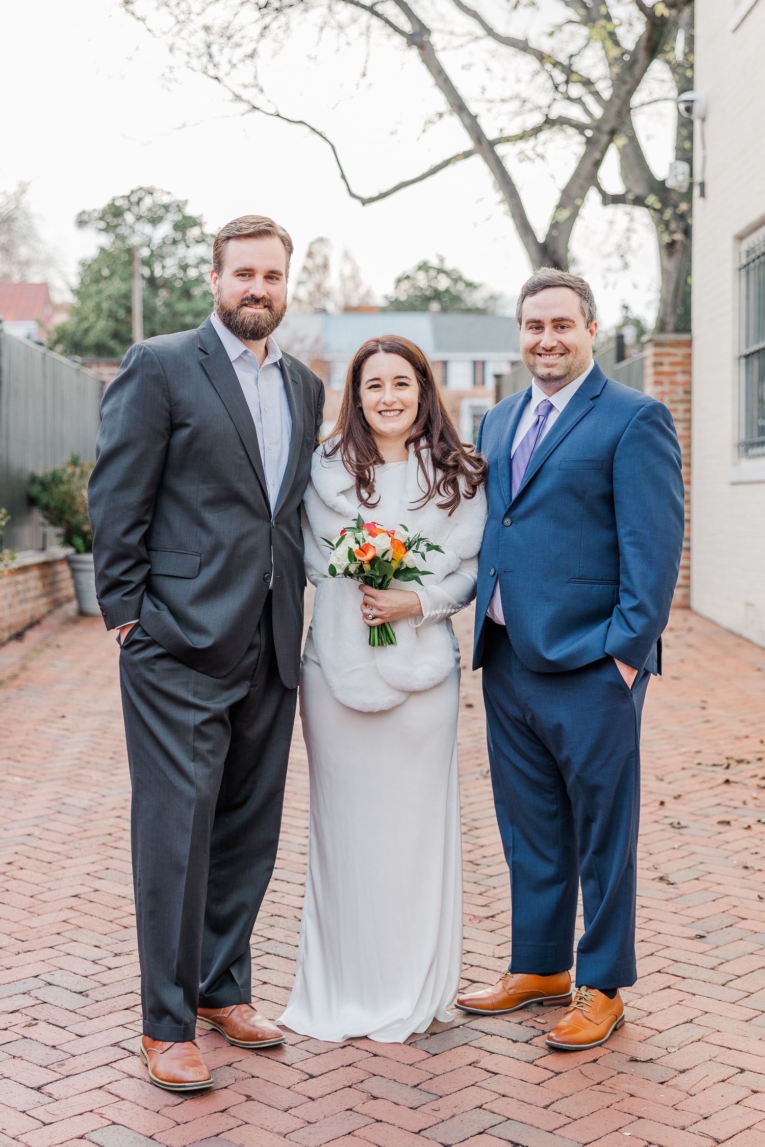 Wedding party in formal attire standing on brick pathway showing shoes and lower legs in coordinated poses.