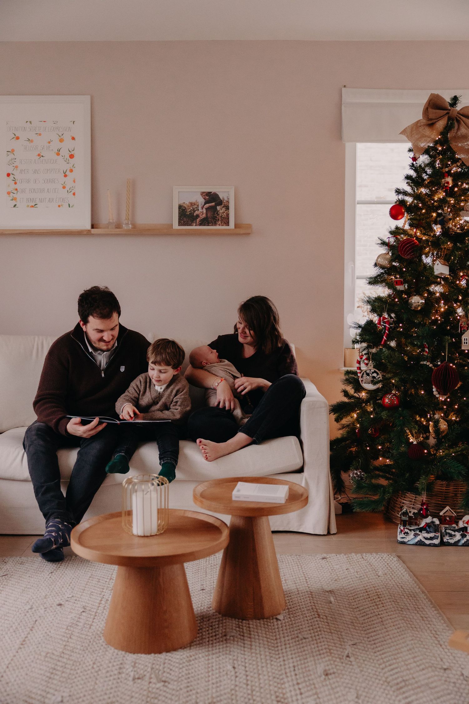 Family of three enjoys cozy Christmas morning together in a festively decorated living room.