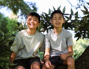 Two siblings sitting in a tree together smiling