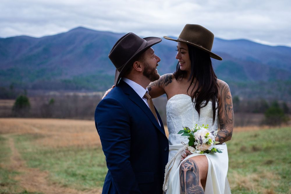 A couple in wedding attire share intimate moments in a scenic mountain landscape during their outdoor wedding celebration.
