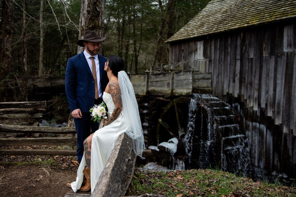A rustic wedding couple poses together in various romantic settings near a weathered barn and wooden fence.