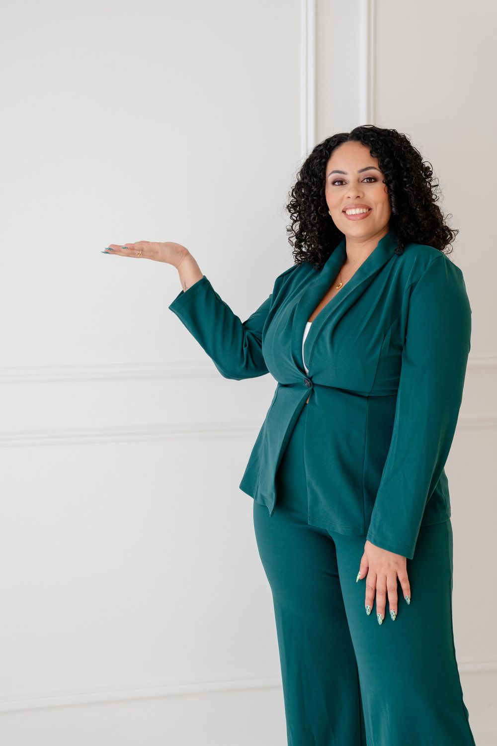 A woman in an elegant emerald green pantsuit poses confidently against a white backdrop in multiple poses.
