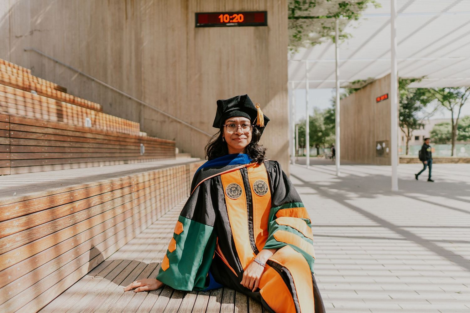 Graduate posing on modern concrete steps with architectural details.