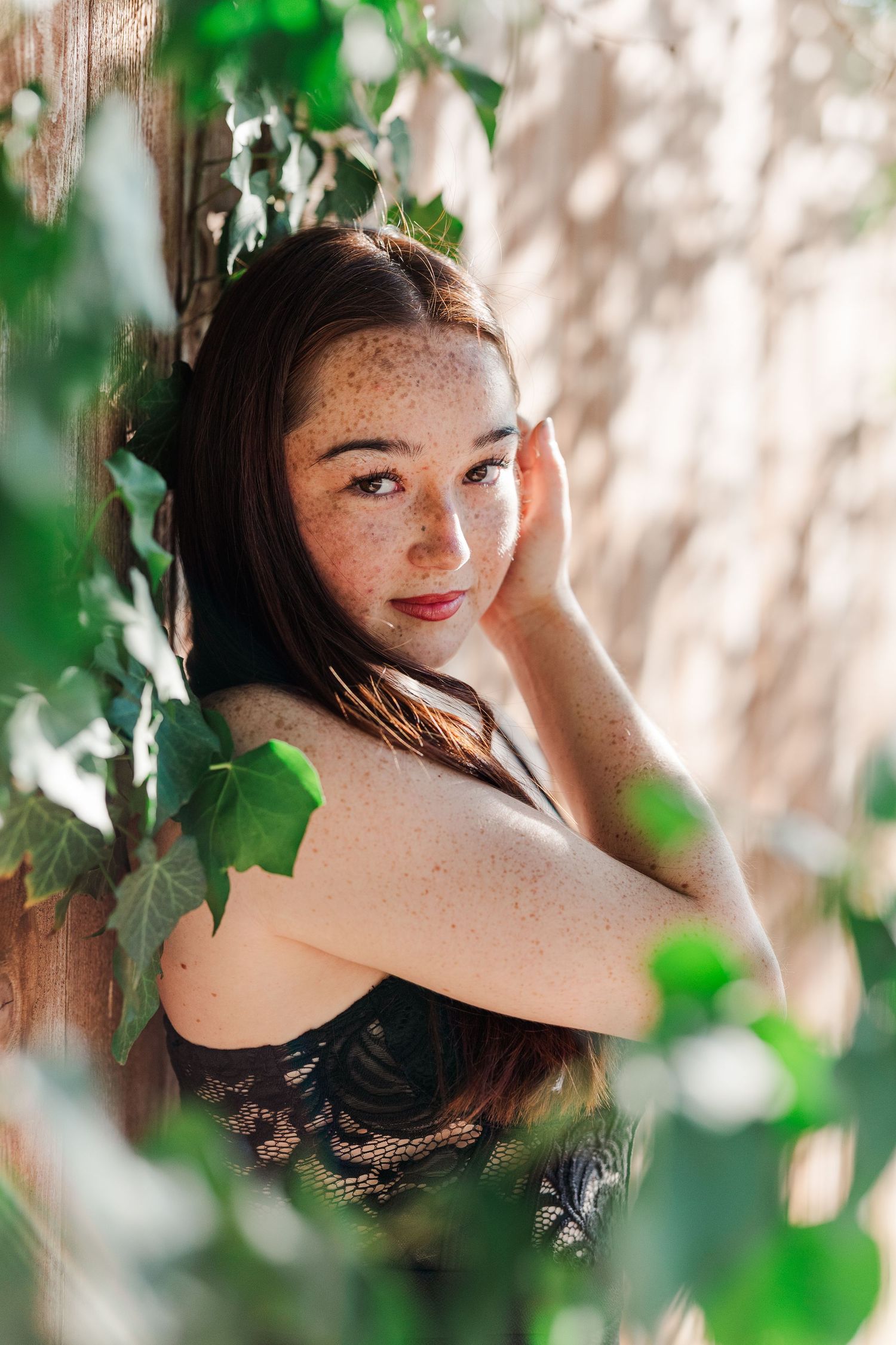 Portrait photo among green ivy leaves and dappled sunlight creating a dreamy natural atmosphere.