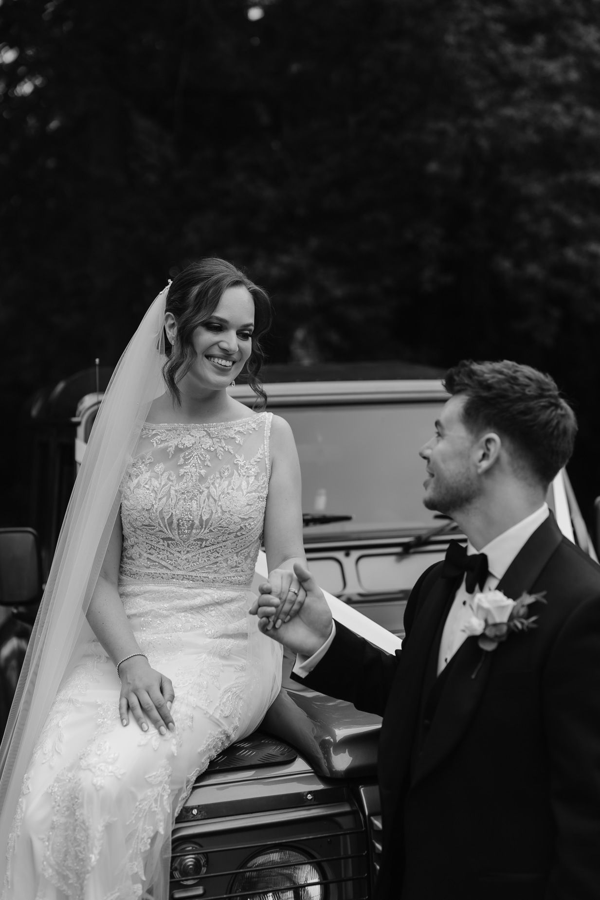 A tender moment shared between a couple near a classic white vintage car.