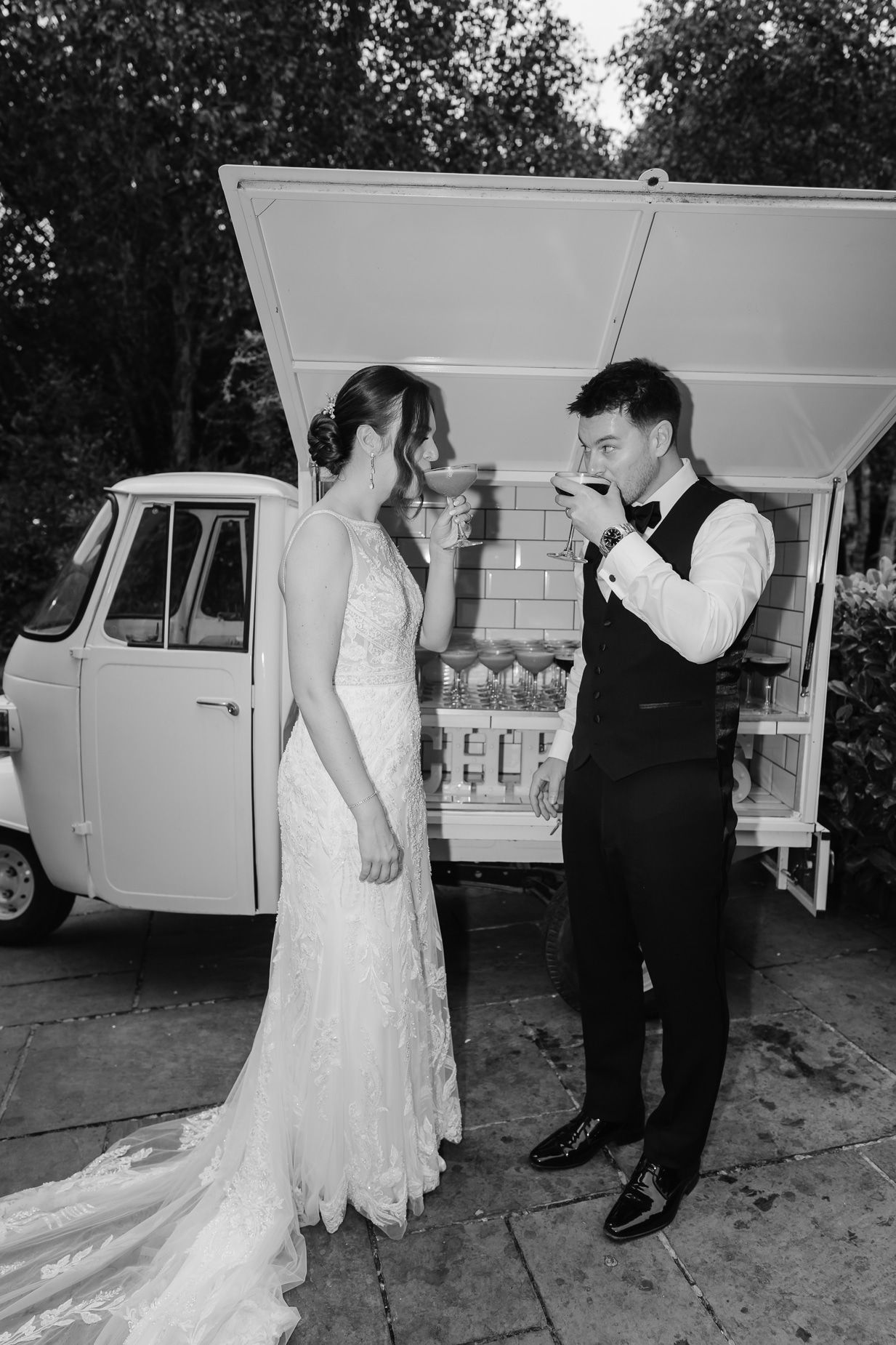 Black and white photos showing tender moments between a couple by a vintage car.