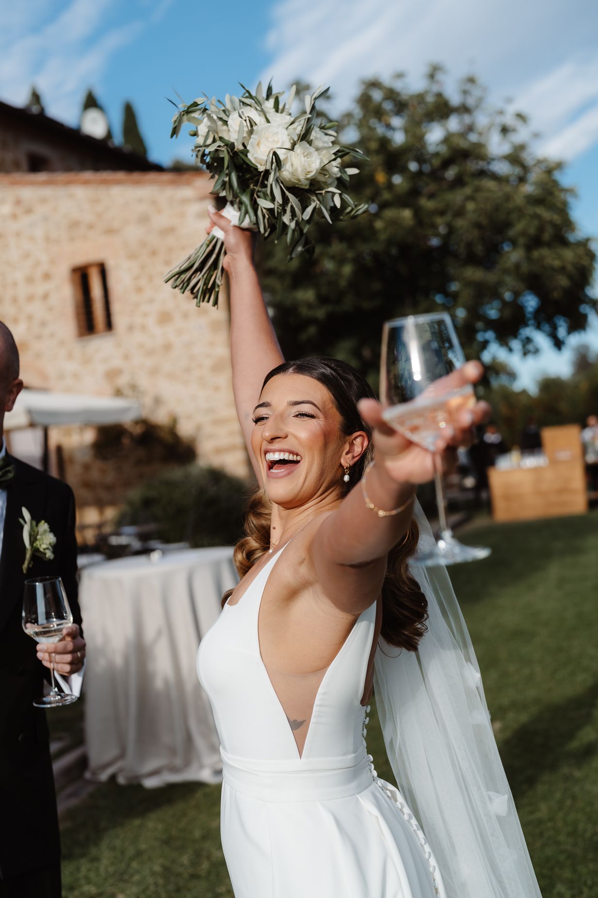 A joyful celebration moment outdoors with champagne and laughter at a wedding reception.