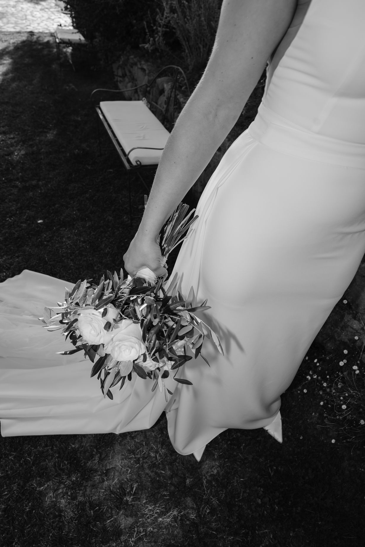 Close-up detail of a white wedding dress and floral bouquet in black and white.