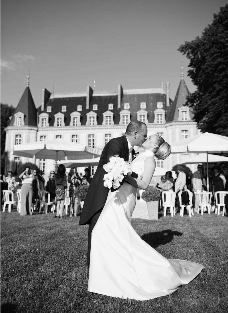 Bride and groom kissing in front of Château de Santeny during a wedding near Paris