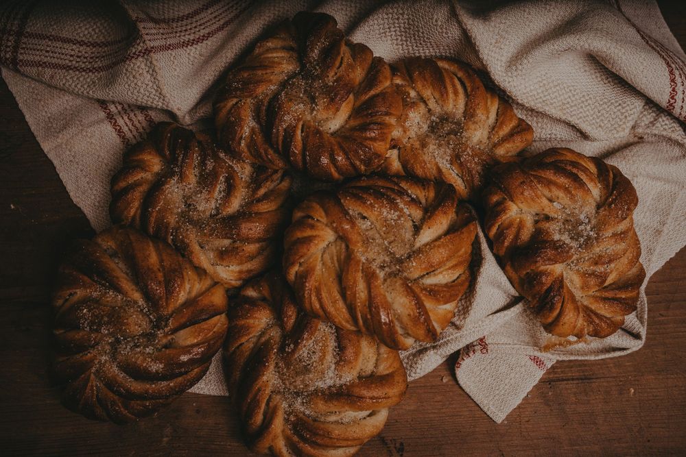 Freshly baked cinnamon rolls with swirls of golden dough arranged on parchment paper.