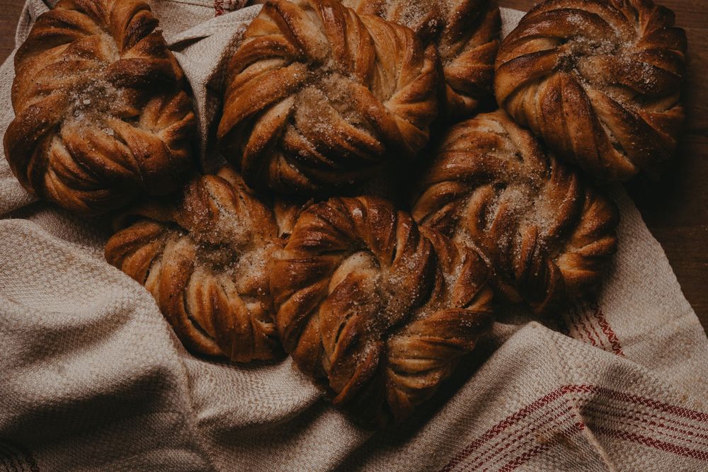 Freshly baked cinnamon rolls with swirled brown sugar filling arranged in a line on a gray cloth.