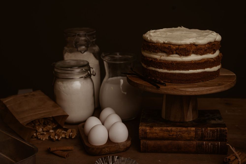 Rustic food photography setup with eggs, cake, and vintage props on dark wooden table with moody lighting.