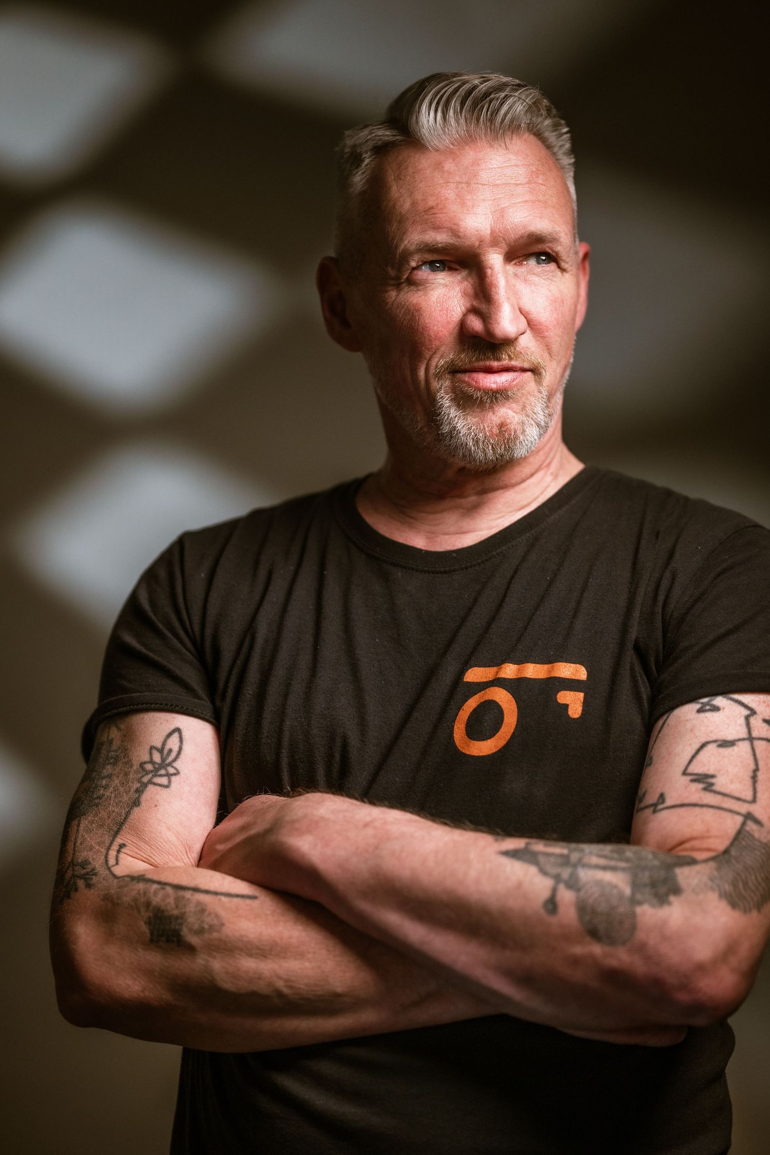 Professioneel portret van ondernemer met zelfverzekerde uitstraling, armen gekruist, warme studioverlichting en neutrale achtergrond