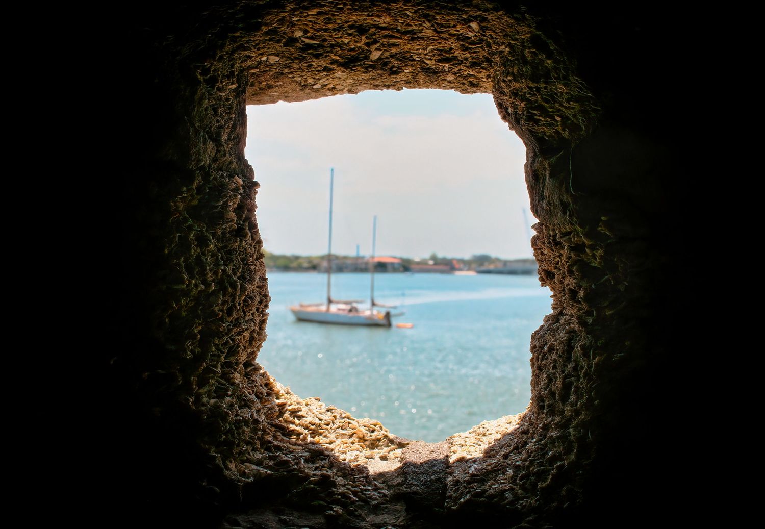 Sailboat on Matanzas Bay viewed through a stone gun port at Castillo de San Marcos in St. Augustine, Florida.