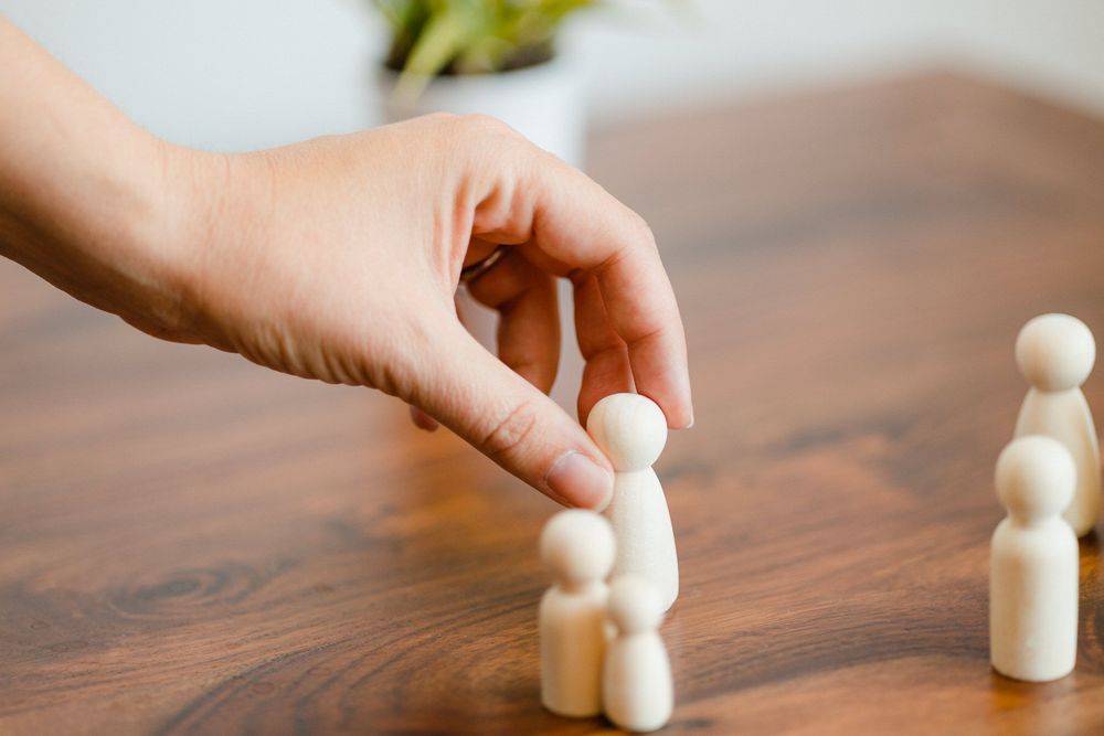 A sequence of photos showing wooden peg dolls being arranged in a line on a dark wooden surface.