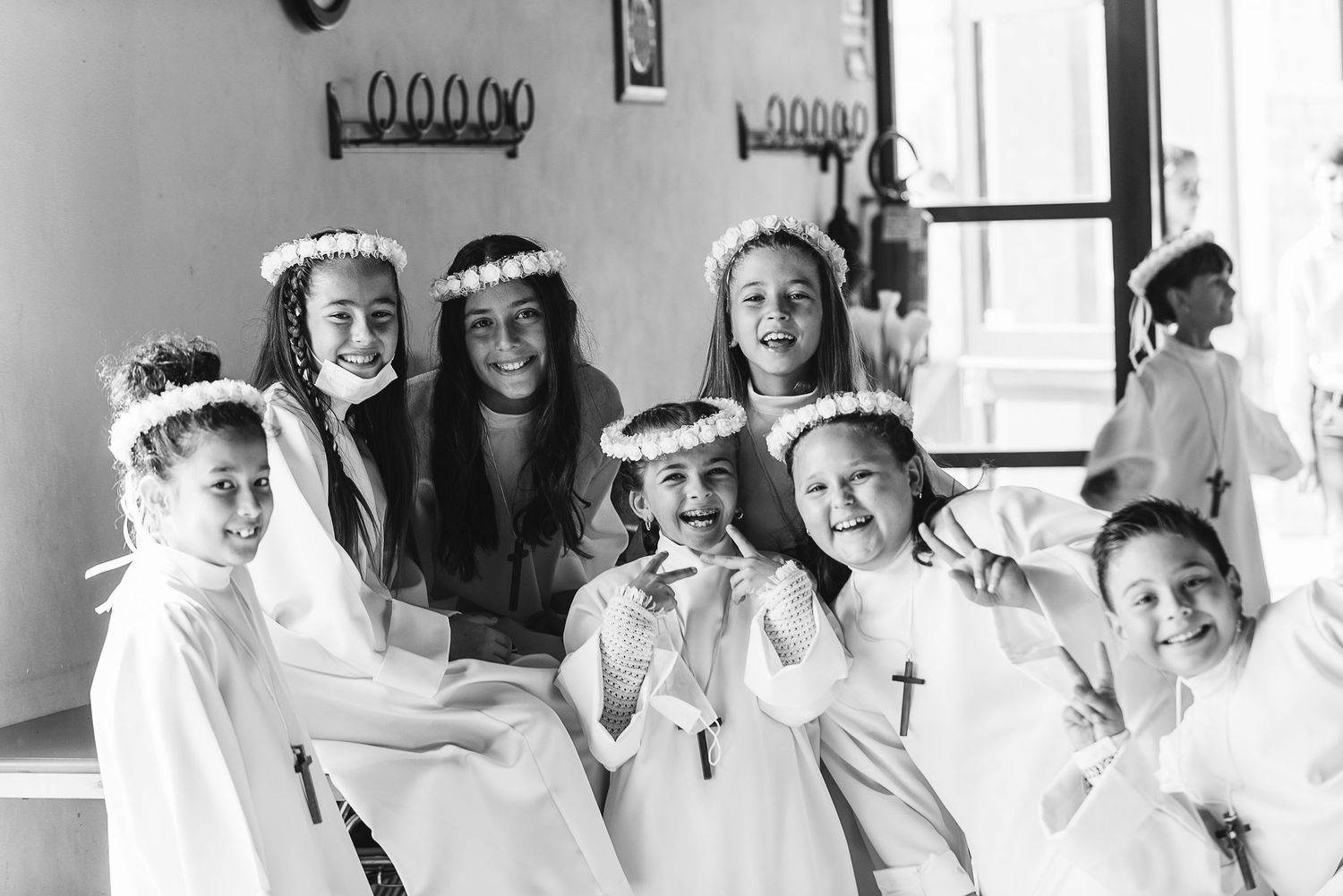 Black and white photo of young people in ceremonial white robes and crowns in a church setting.