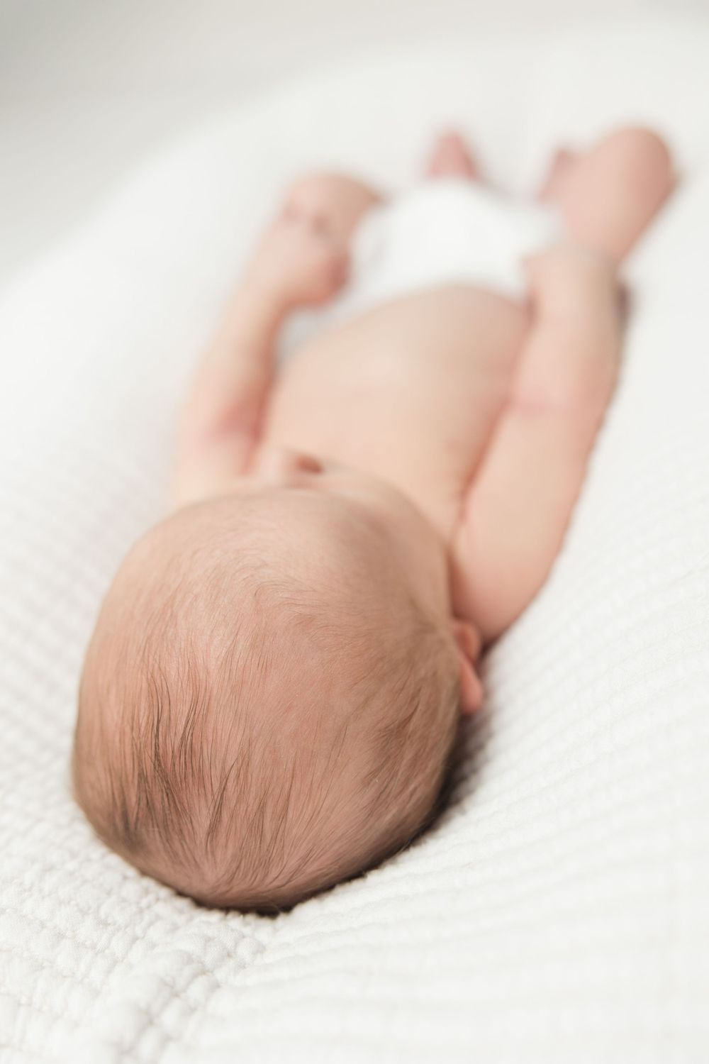 Newborn baby sleeping peacefully on white textured blanket shown from different angles.