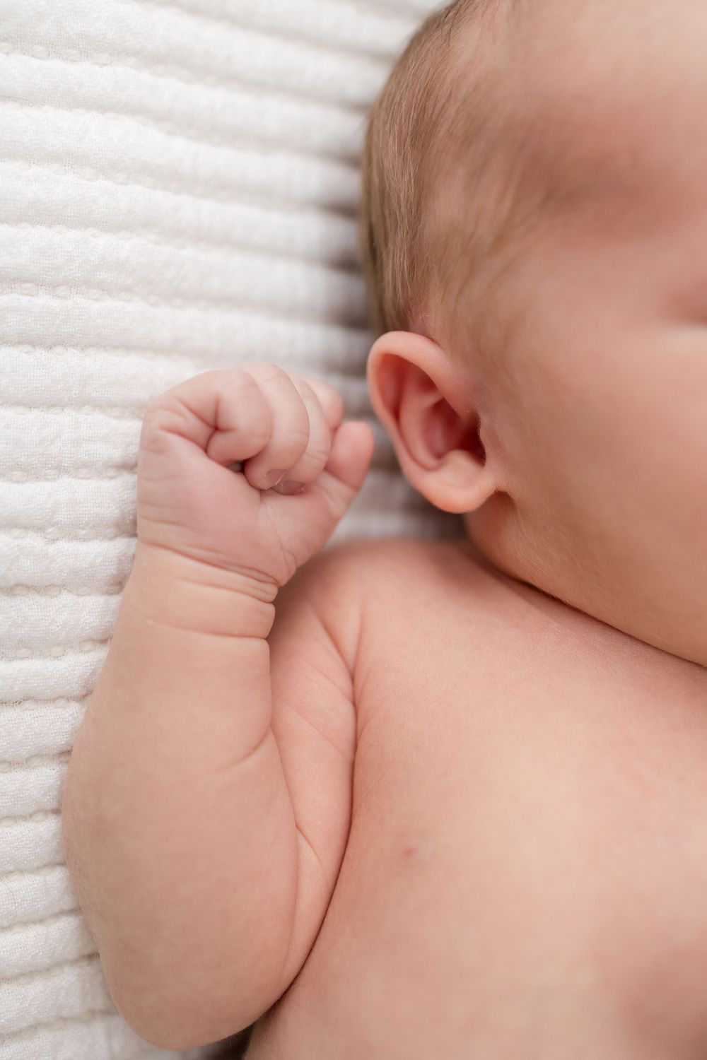Close-up series of a sleeping baby's delicate features against white textured fabric.