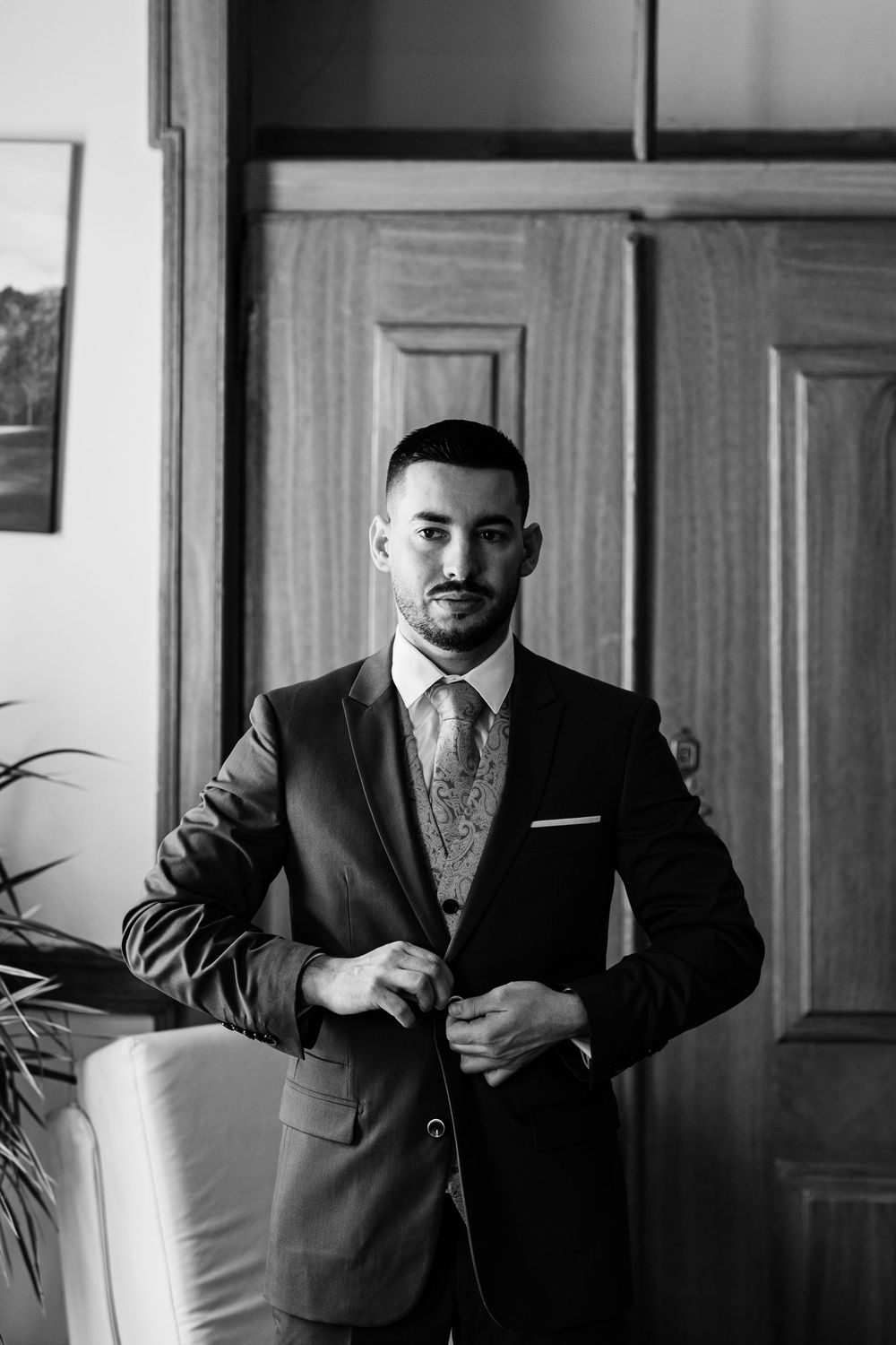 Groom adjusting his suit while his grandfather watches proudly in Almada