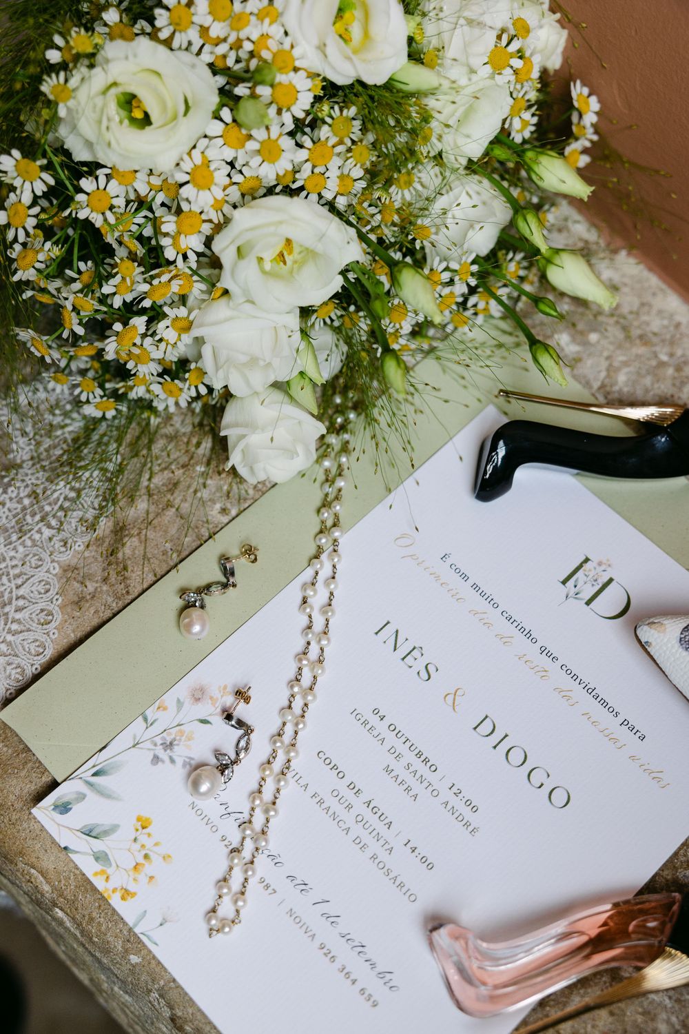 White roses and yellow flowers decorate elegant wedding invitation cards with gold calligraphy text on cream paper.