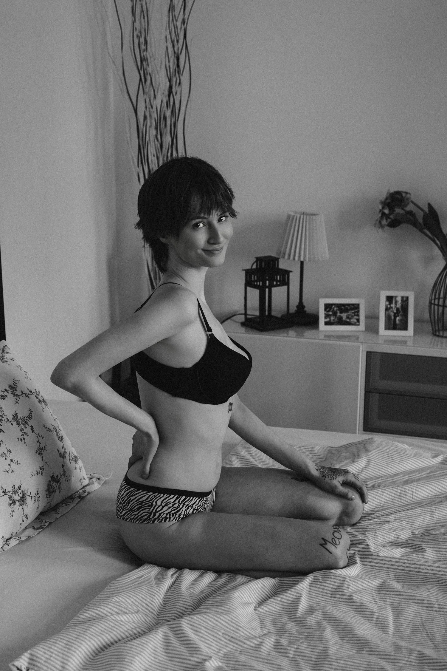 A black and white photo series shows someone in casual attire lounging on a bed in different relaxed poses.