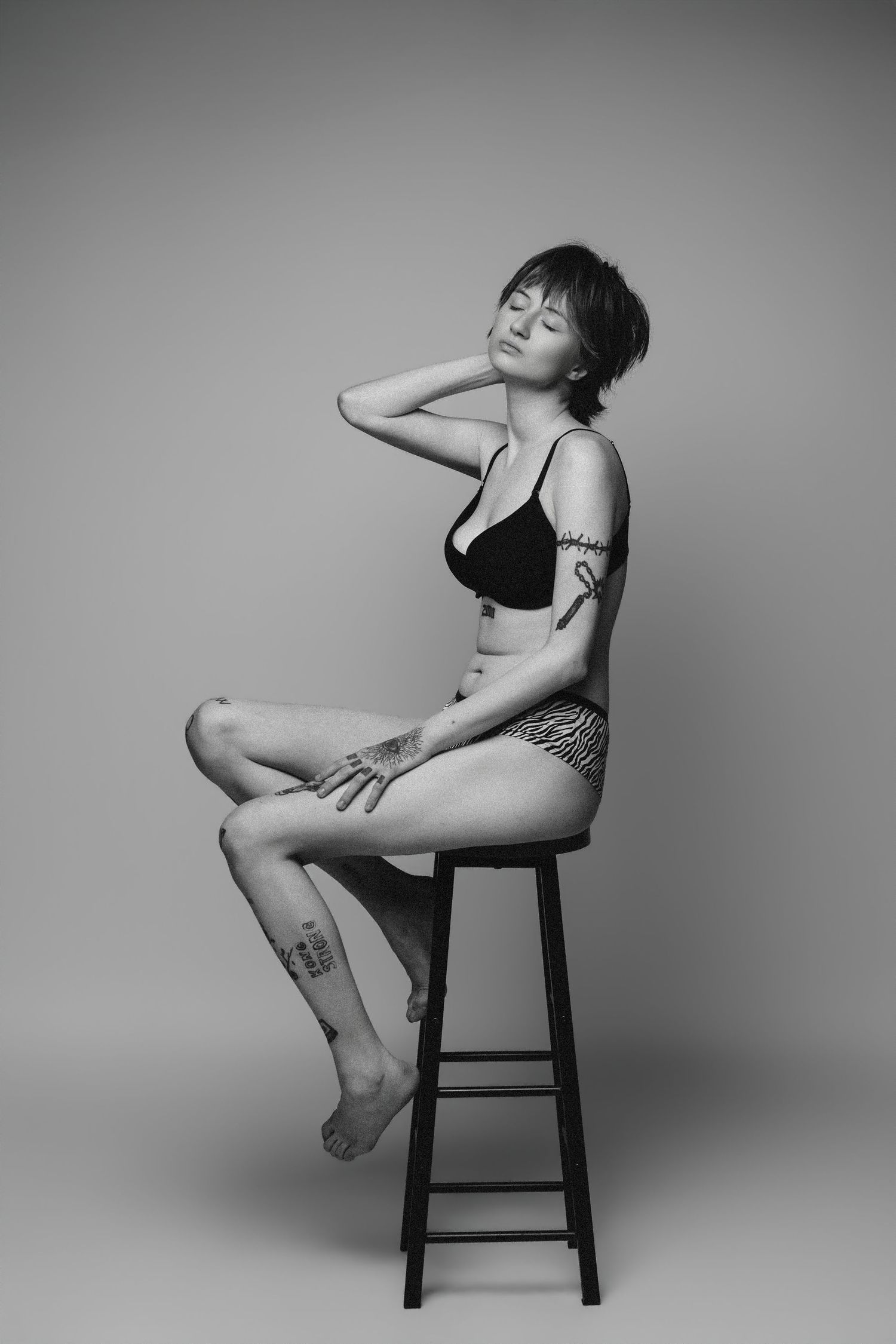 Artistic black and white photo series showing graceful poses on a wooden stool against a minimalist studio backdrop.