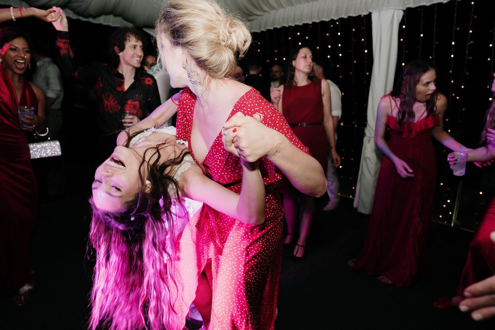 Sposa sollevata durante il party serale tra amici e damigelle vestite di rosso a Imperia